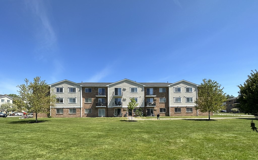 A large apartment complex with a grassy lawn in front.